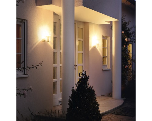 Façade éclairée d''une maison avec deux lampes d''extérieur près de la porte d''entrée.