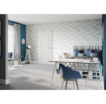 Chambre lumineuse avec lit, bureau et mur de briques