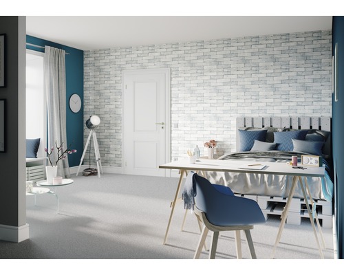 Chambre lumineuse avec lit, bureau et mur de briques