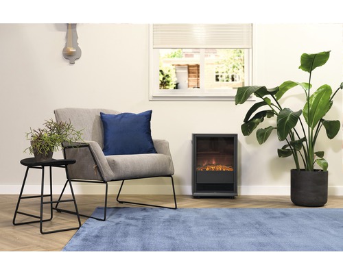 Wohnzimmer mit Sessel, Kissen, Tisch, Zimmerpflanzen, Elektrokamin und Teppich