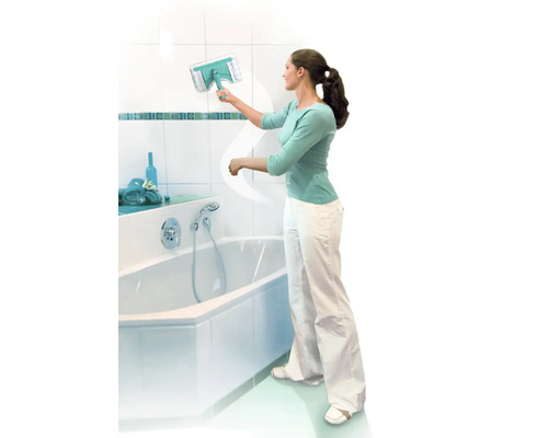 Une femme nettoie le carrelage de la salle de bains avec un lave-vitre à côté d''une baignoire.