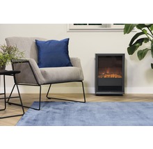 Wohnzimmer mit Sessel, Zierkissen, Beistelltisch, Zimmerpflanze, Teppich und Elektrokamin
