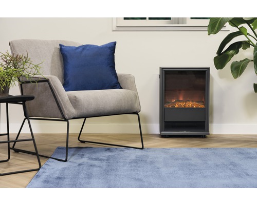 Wohnzimmer mit Sessel, Zierkissen, Beistelltisch, Zimmerpflanze, Teppich und Elektrokamin