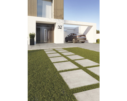 Moderne Hausansicht mit Betonplattenweg durch Rasenfläche und einem Auto im Carport