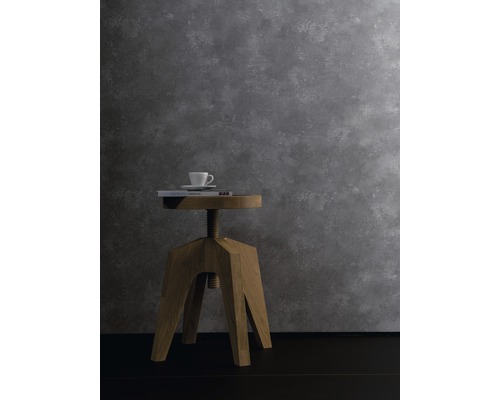 Scène décorative avec tabouret en bois, livre et tasse devant un mur gris