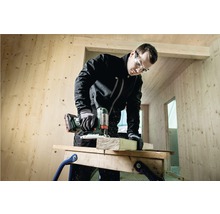 Un artisan coupe du bois avec une scie sauteuse dans une maison en bois.