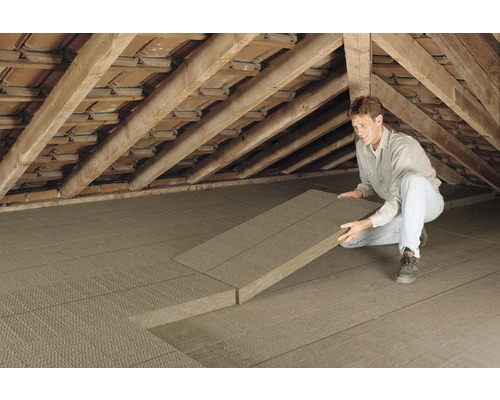 Un homme pose des panneaux isolants dans un grenier pour l''isolation thermique.