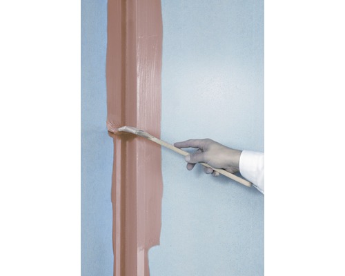 Une personne peint une latte sur un mur avec un pinceau.