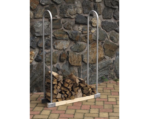 Range-bûches avec bûches devant un mur en pierre