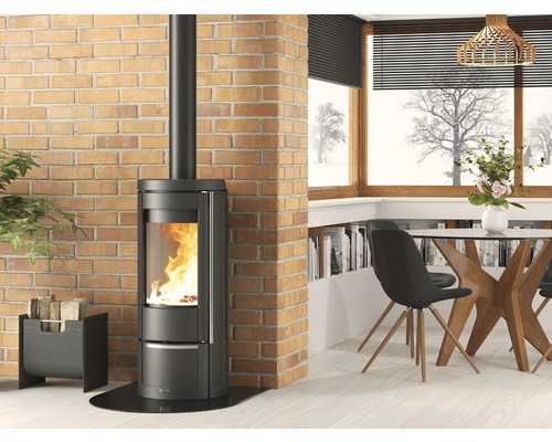 Kaminofen in einem hellen Wohnraum mit Ziegelwand und Essbereich.