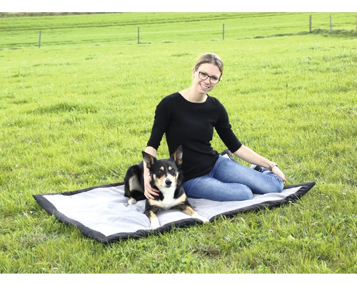 Une femme est assise avec son chien sur une couverture pour chien à l''extérieur.