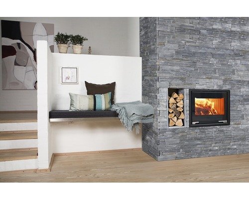 Wohnzimmer mit Steinwand, Kamin, Holzscheiten und Sitzbank