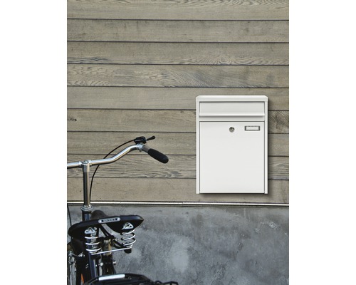 Weißer Briefkasten neben einem Fahrrad an einer Wand montiert