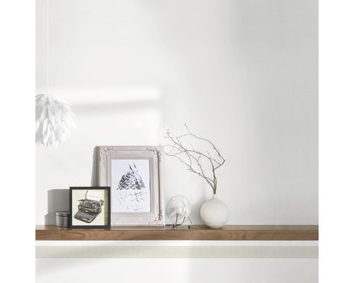 Bordure décorative dans une pièce avec cadres photo, vase et lampe.