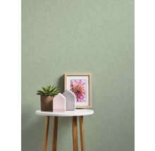 Dekorative Szene mit Pflanze, Bilderrahmen und Hausfiguren auf einem Tisch vor einer Wand