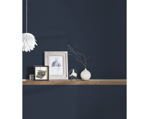 Objets décoratifs tels que des cadres, un ventilateur et un vase sur une étagère murale devant un mur sombre.