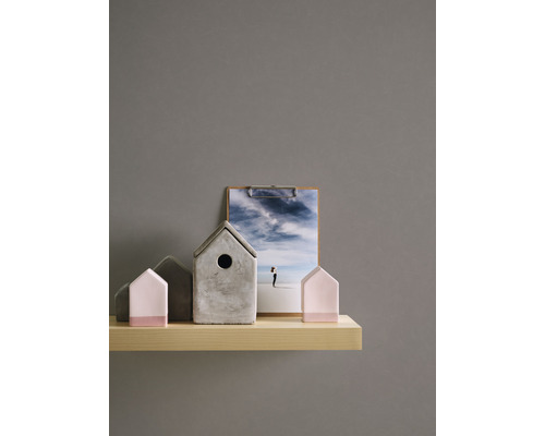 Dekorative Häuser aus Beton und Holz auf einem Regal mit einem Foto auf einem Klemmbrett.