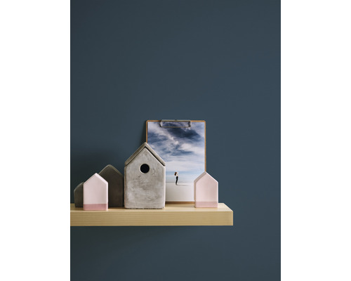 Maisons décoratives en béton et en bois sur une étagère, avec une photo sur un presse-papiers.