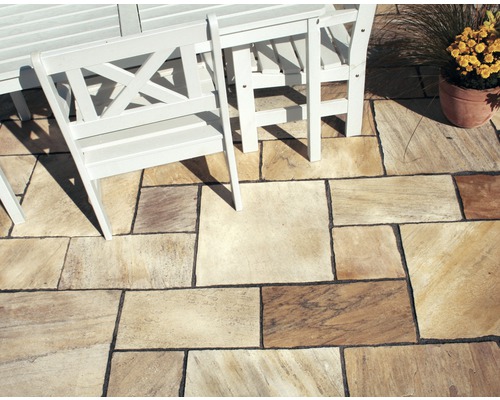 Verlegtes Natursteinpflaster im Aussenbereich mit Sitzgruppe und Blumentopf.