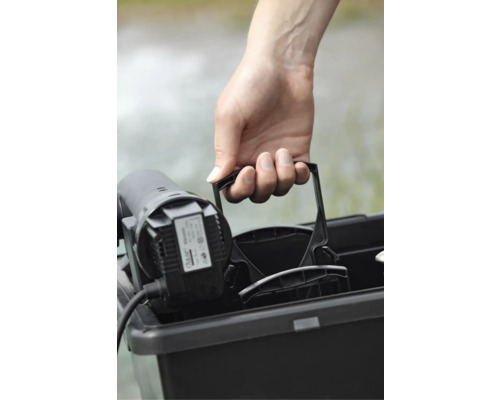 Main soulevant une pompe de bassin dans un récipient noir