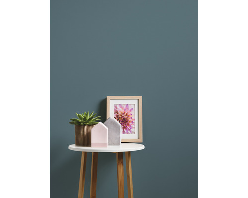 Dekoration mit Topfpflanze, Bilderrahmen und Dekohäusern auf einem kleinen Tisch.