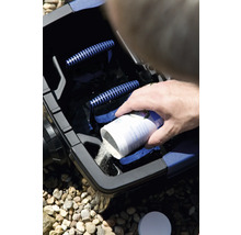 Person gibt ein Teichpflegeprodukt in einen Teichfilter.