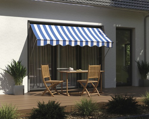 Terrasse avec store, table et chaises devant un mur de maison