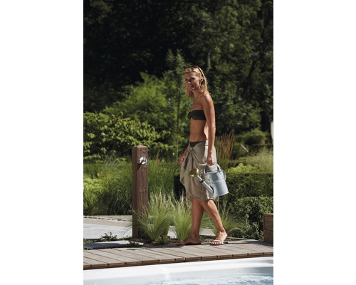 Frau mit Giesskanne in einem Garten mit Wasserhahn