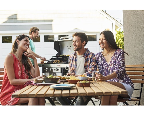 Groupe d''amis faisant un barbecue et mangeant ensemble à l''extérieur.