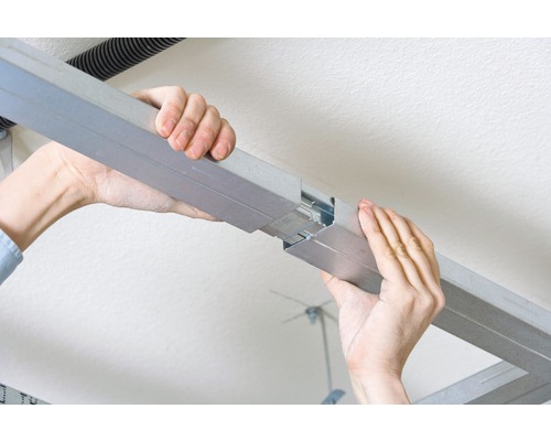 Personne connectant des profilés de construction sèche pour montage au plafond