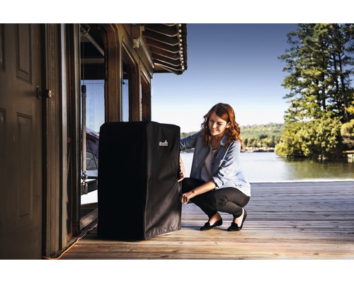 Housse de protection pour barbecue avec femme sur terrasse en bois au bord du lac