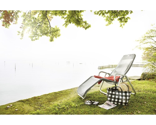 Scène avec chaise longue, sac de plage et lac en arrière-plan