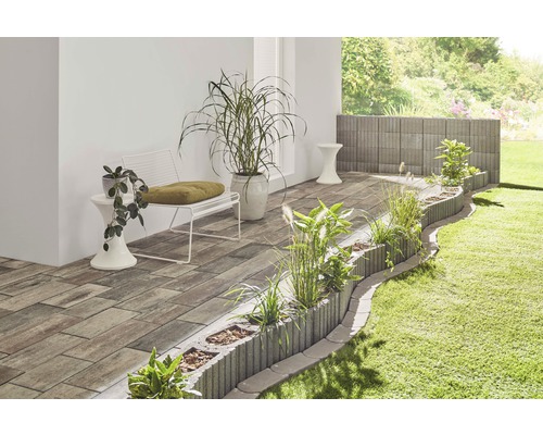 Aménagement extérieur avec pavés, bacs à fleurs, banc et plantes