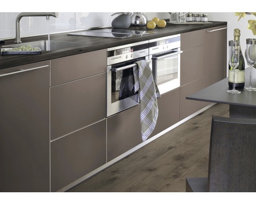 Moderne Küche mit Spüle, Kochfeld, Backofen und Esstisch.