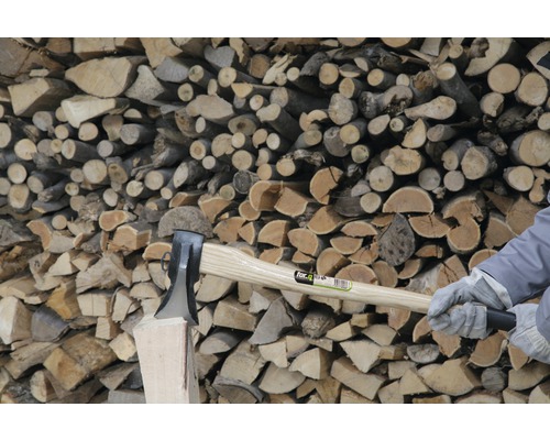 Hache pour fendre le bois devant une pile de bois