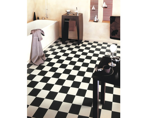 Salle de bain avec motif de carreaux en damier noir et blanc, baignoire et lavabo