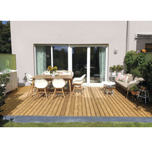 Terrasse avec plancher en bois, table de jardin et chaises devant une maison