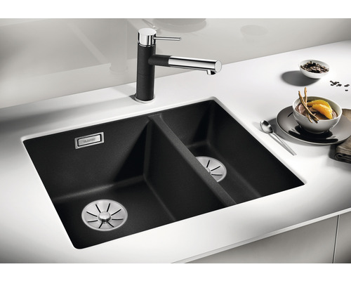 Schwarzes Doppelspülbecken mit Wasserhahn auf einer weißen Arbeitsplatte.