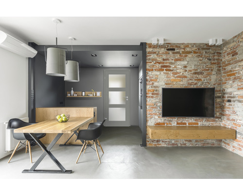 Salon moderne avec table à manger, chaises, porte et télévision sur mur de briques