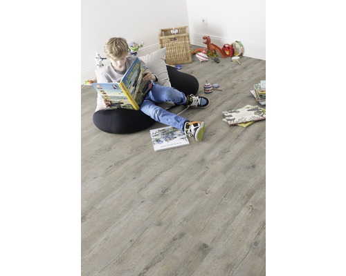 Un garçon lit un livre sur un plancher en bois clair dans une chambre d''enfant.