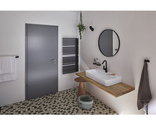 Helles Badezimmer mit Waschbecken auf Holztischplatte, Heizkörper, Spiegel und Tür