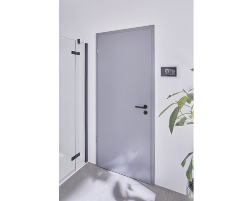 Graue Innentür mit schwarzem Türgriff in einem hellen Raum