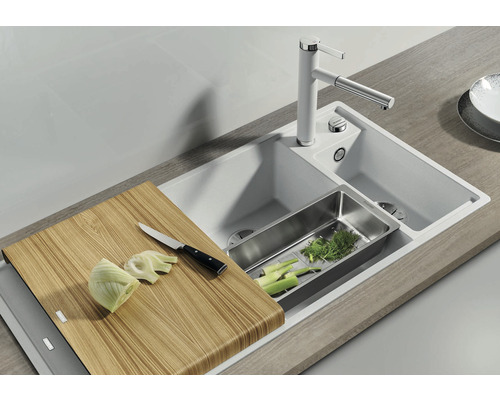 Spüle mit Schneidebrett, Abtropfschale und Armatur in einer hellen Küchenumgebung.