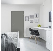 Graue Innentür in einem hellen Schlafzimmer mit Bett, Schreibtisch und Stuhl