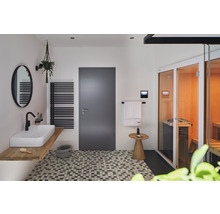 Helles Badezimmer mit Waschbecken, Spiegel, Heizkörper, Tür und Sauna.