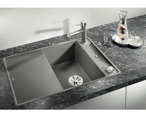 Évier en granit avec égouttoir et robinet sur un plan de travail.