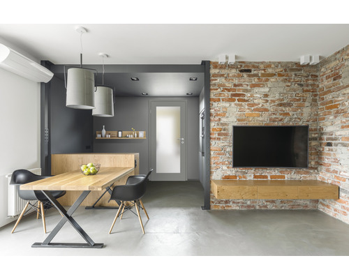 Salon moderne avec table à manger, chaises, télévision et mur de briques