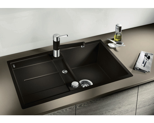 Dunkles Küchenspülbecken mit Abtropffläche und Armatur auf einer Küchentheke.