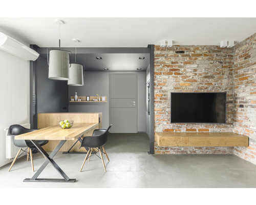 Helles Wohnzimmer mit Esstisch, Stühlen, Backsteinmauer und Fernseher