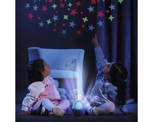 Deux enfants sont assis dans le noir et regardent une projection d''étoiles sur le mur, créée par un projecteur.